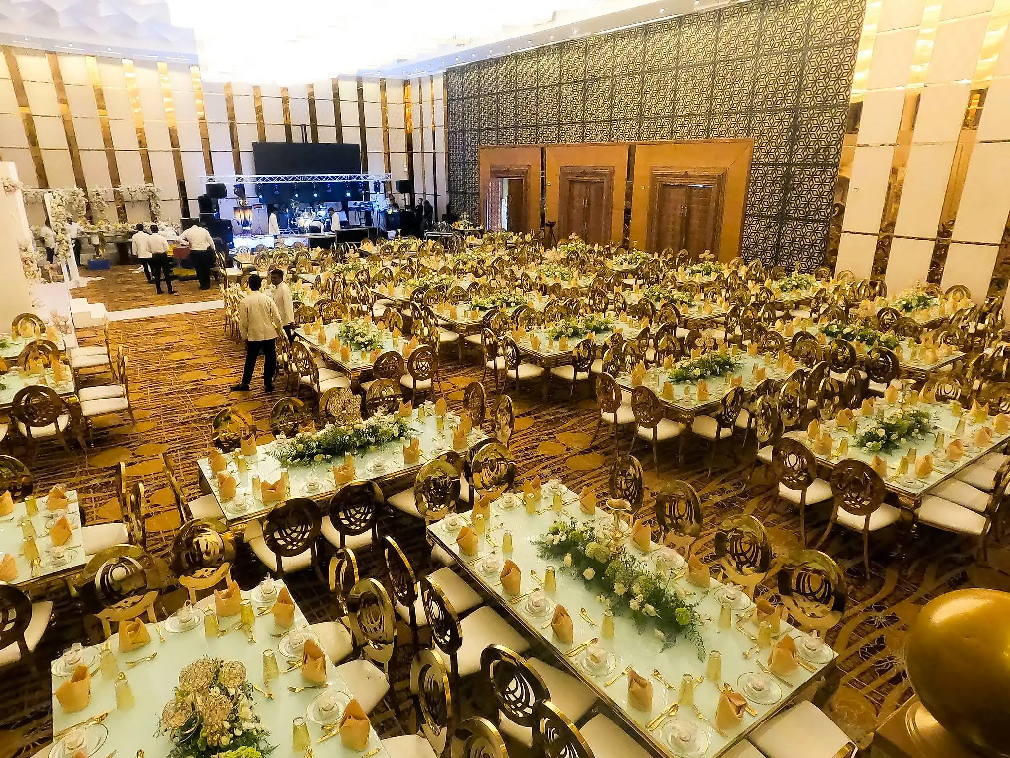 The Grand Ballroom set for a reception, with gold chairs, white florals and a live band stage