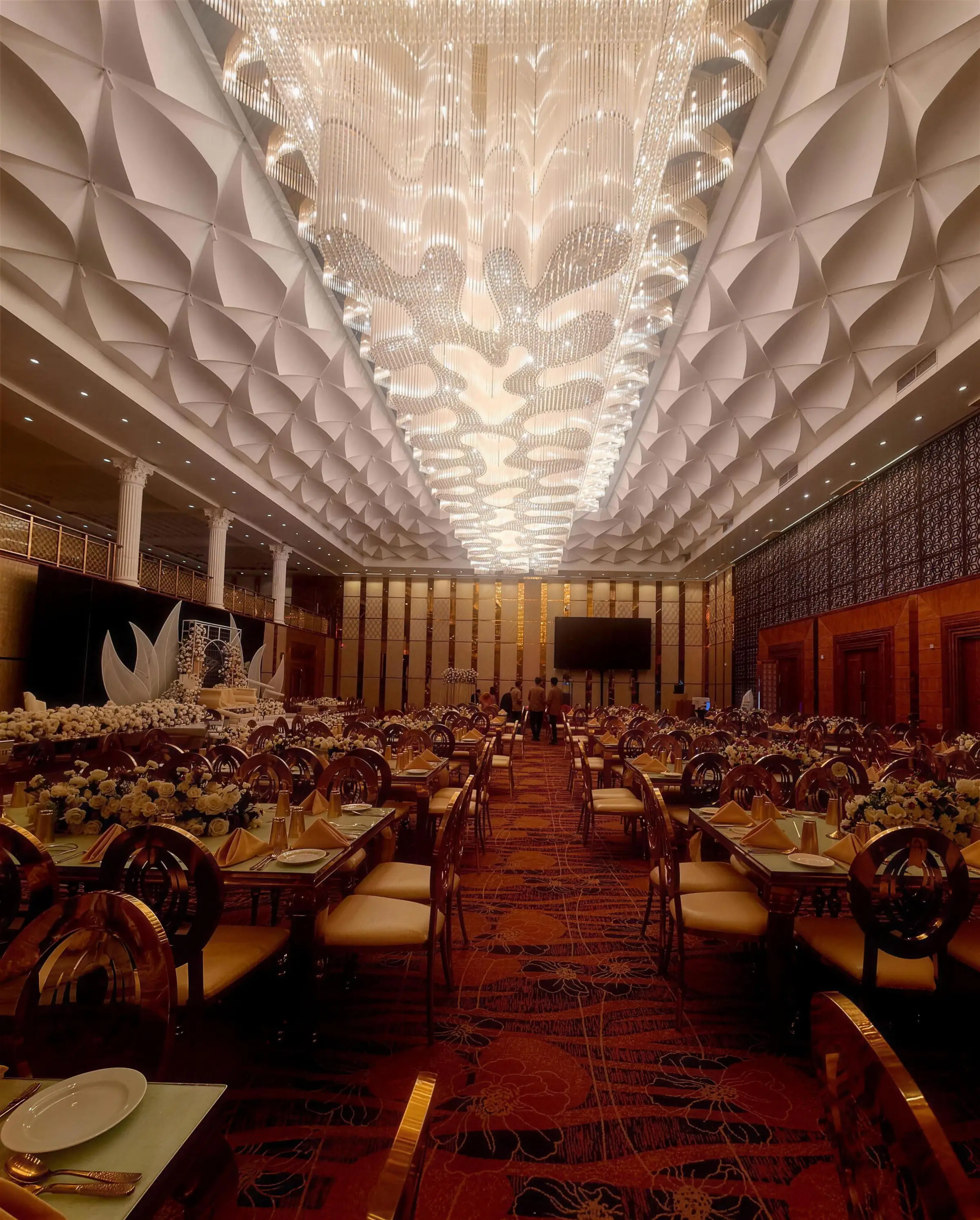 The Grand Ballroom beneath its cascading crystal chandelier and sculpted lotus ceiling, laid for a wedding
