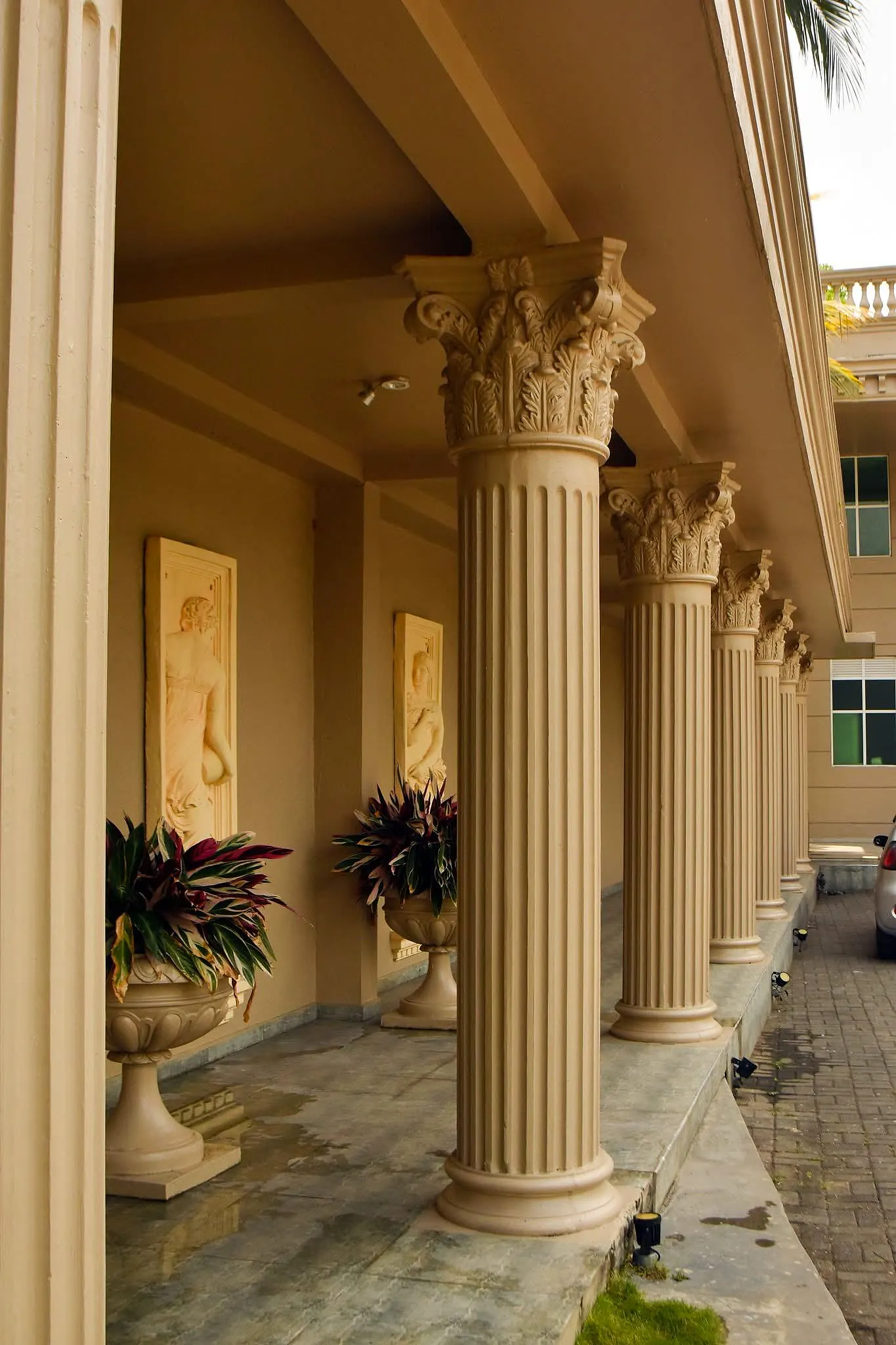 A Corinthian colonnade with classical relief panels and planted urns