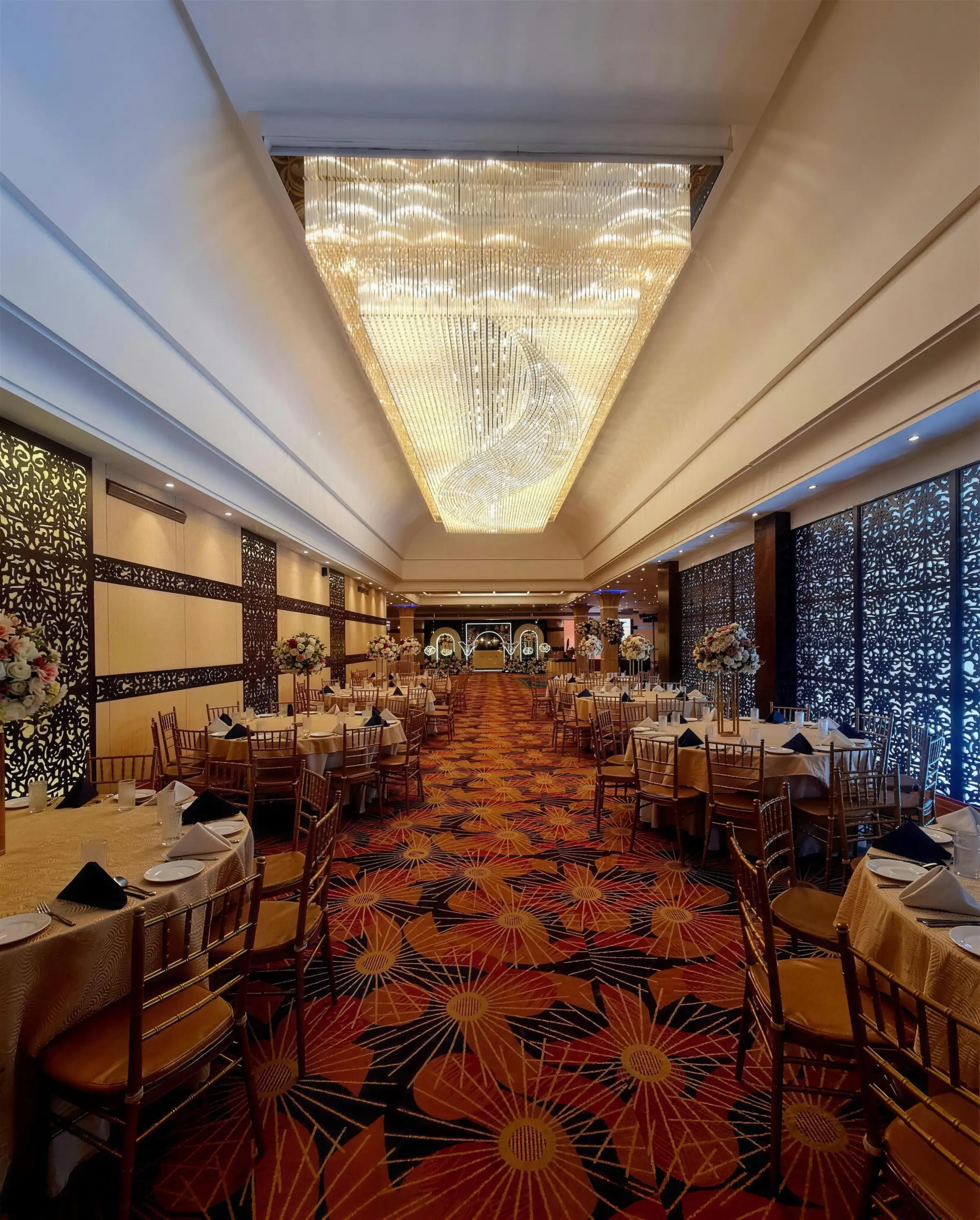The Royal Pavilion, a long crystal chandelier above round banquet tables and carved lattice screens